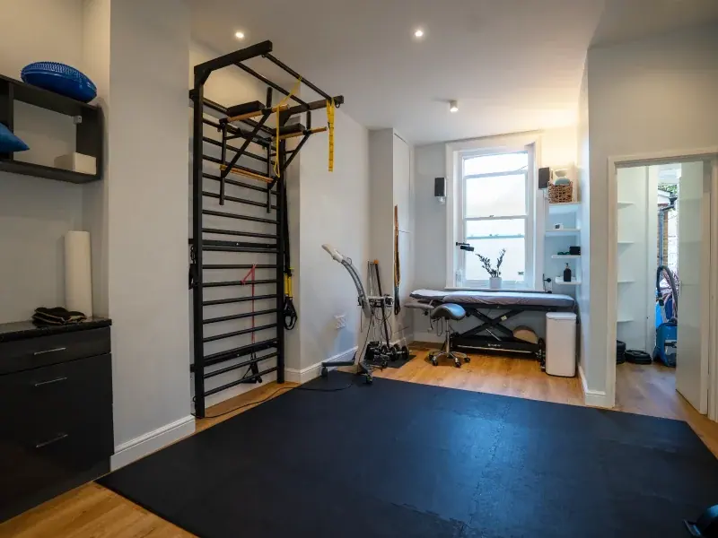 PhysioB exercise space with wall bars and a treatment bed by the window